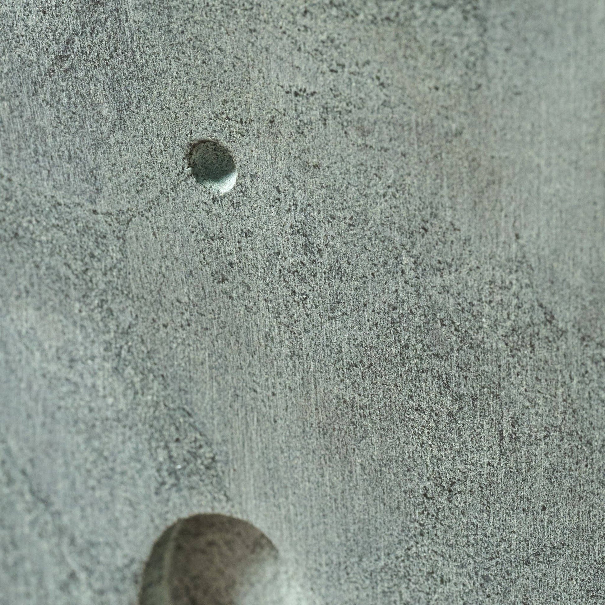 Close-up of a textured surface with a small circular object on a gray background
