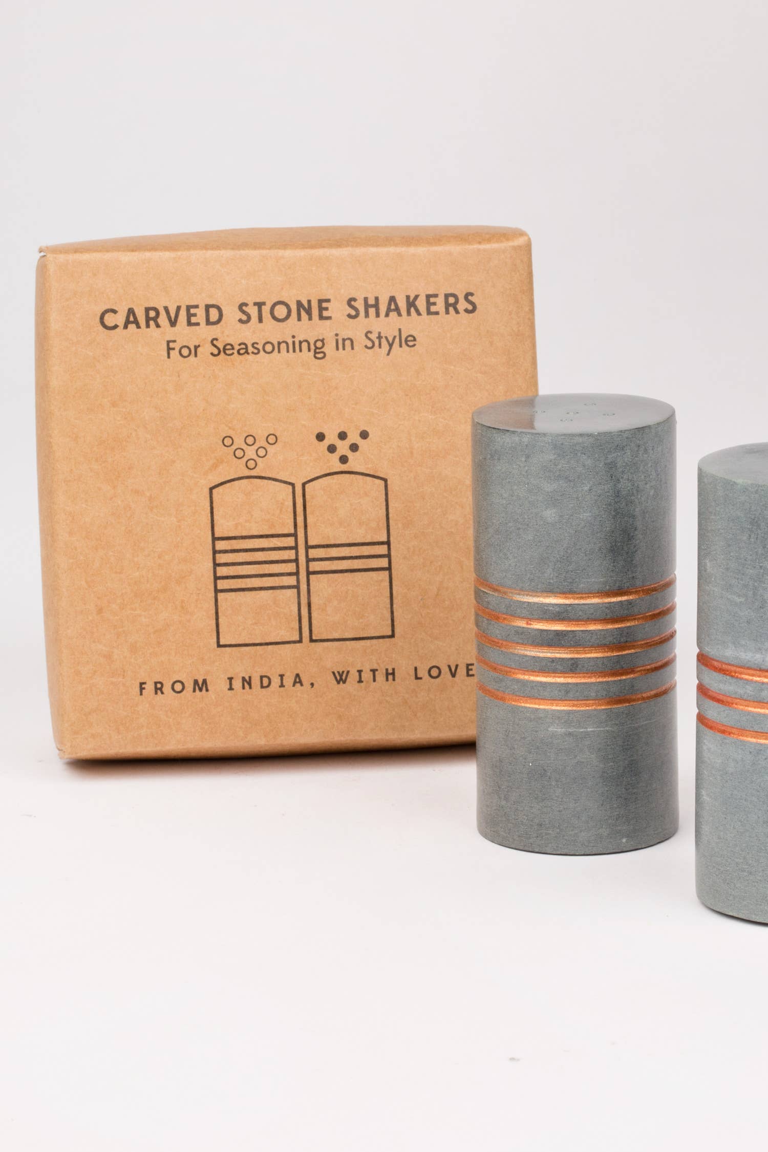 Carved stone shakers with a cardboard box on a white background