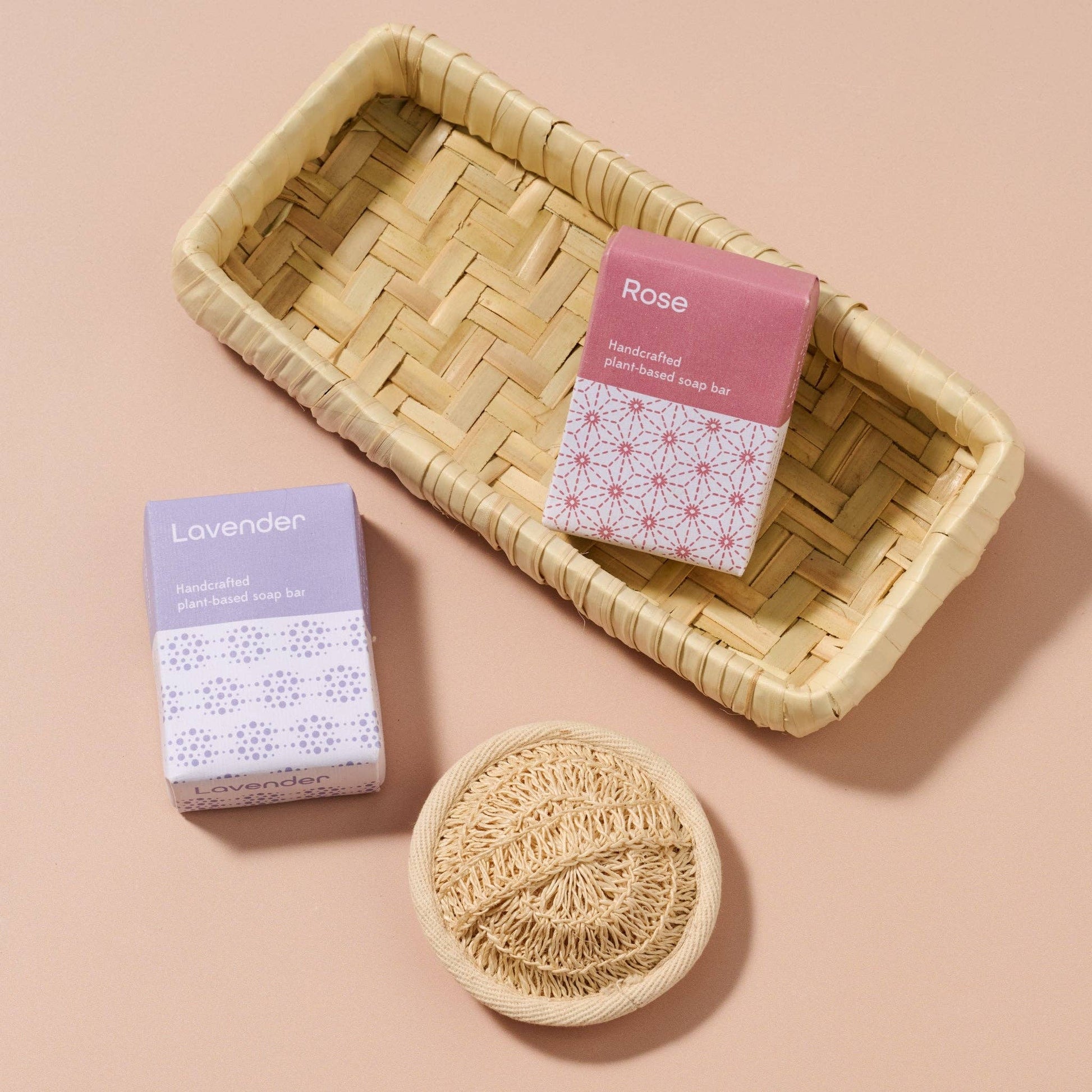 Handmade soap bars in boxes with a woven dish on a beige background