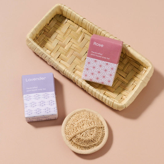 Handmade soap bars in boxes with a woven dish on a beige background