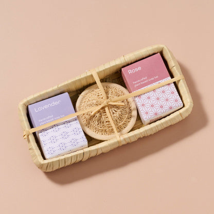 Set of soap bars with a natural sponge in a woven basket on a beige background