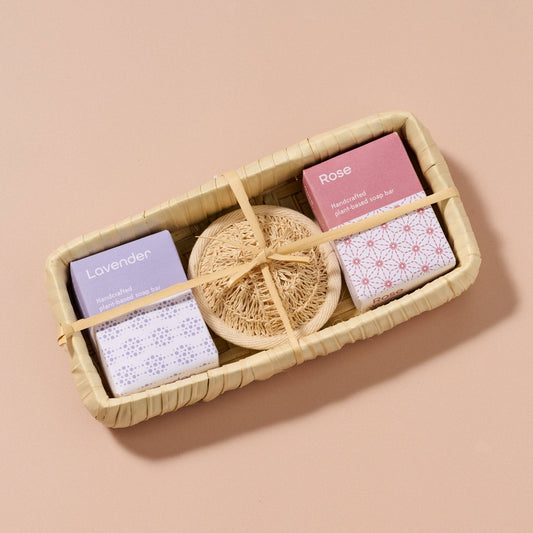 Set of soap bars with a natural sponge in a woven basket on a beige background