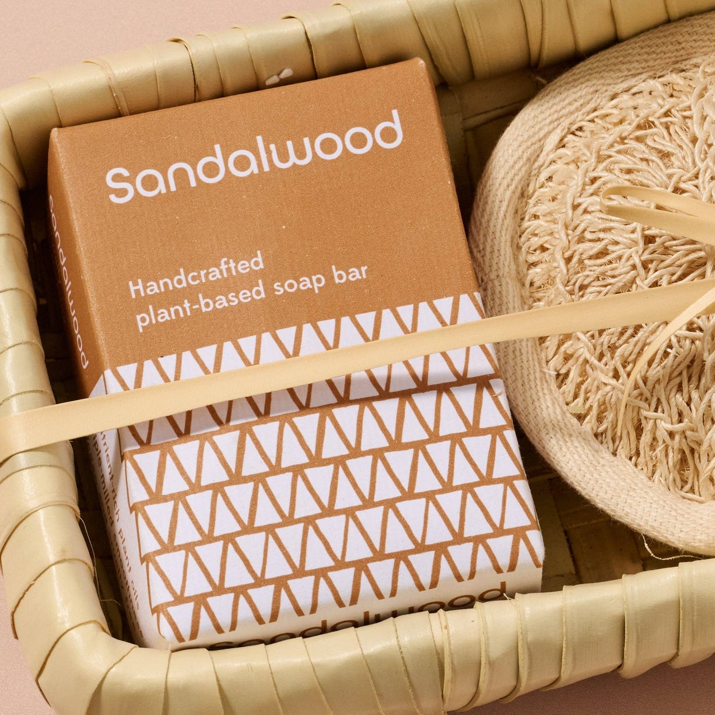 Handcrafted plant-based soap bar in a brown box with geometric pattern, surrounded by natural elements.