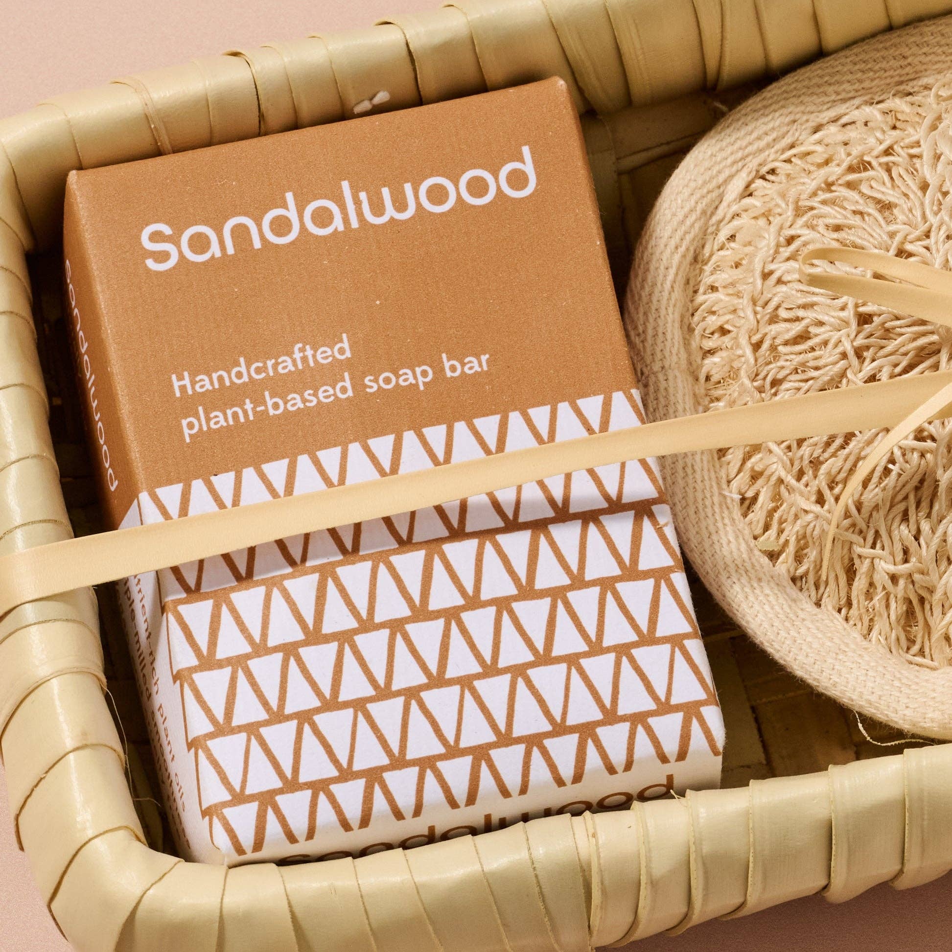 Handcrafted plant-based soap bar in a brown box with geometric pattern, surrounded by natural elements.