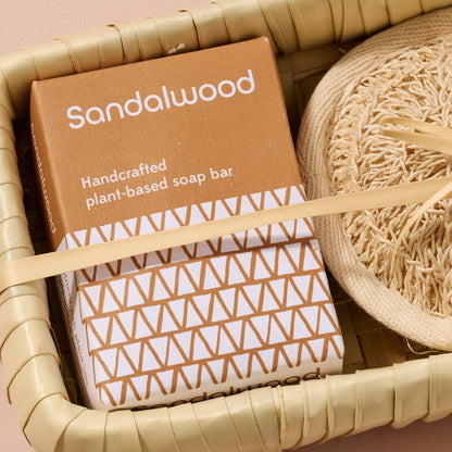 Handcrafted plant-based soap bar in a brown box with geometric pattern, surrounded by natural elements.