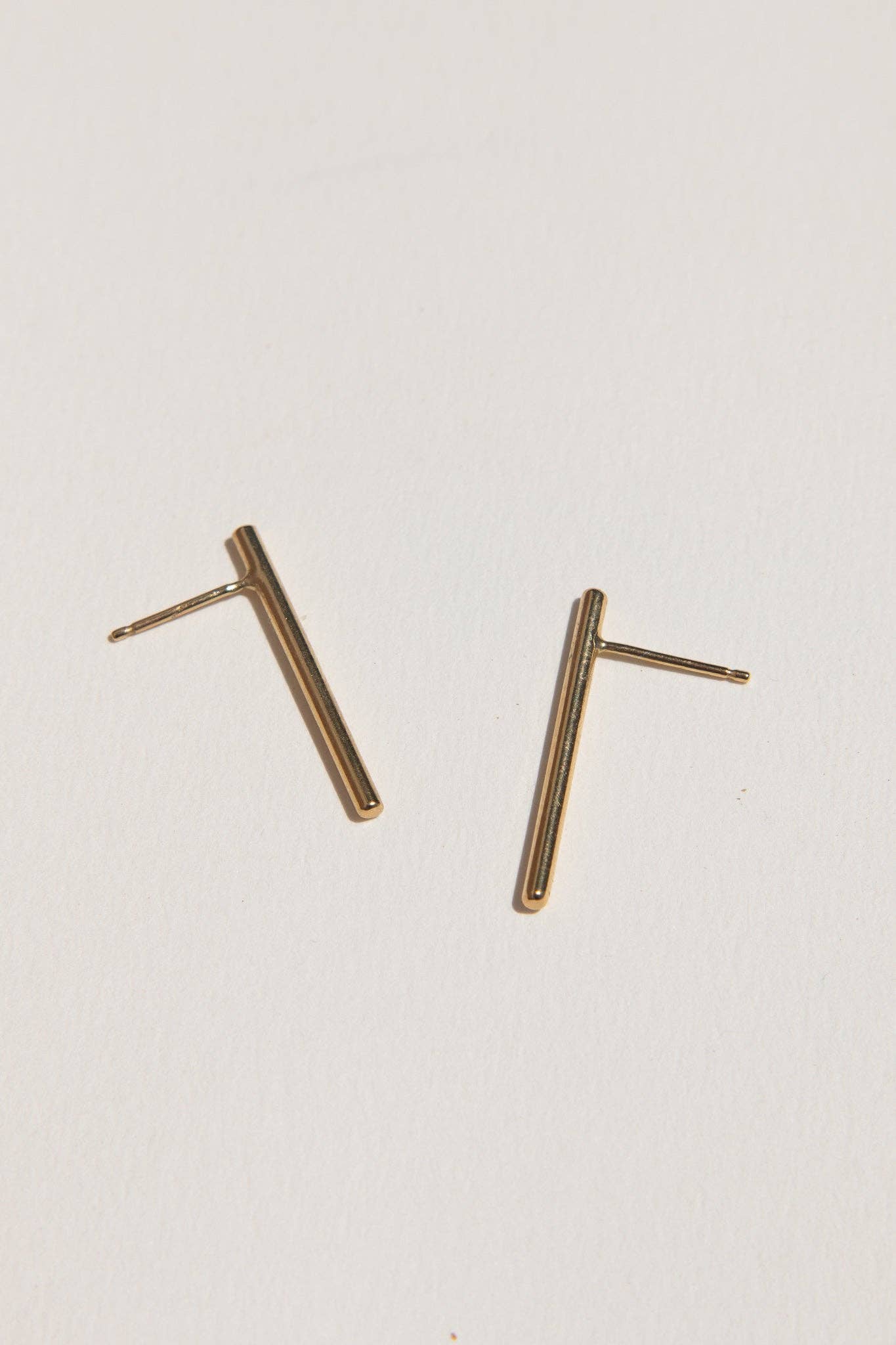 Pair of gold bar earrings on a light gray background
