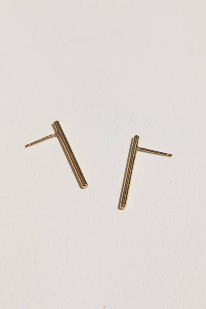 Pair of gold bar earrings on a light gray background