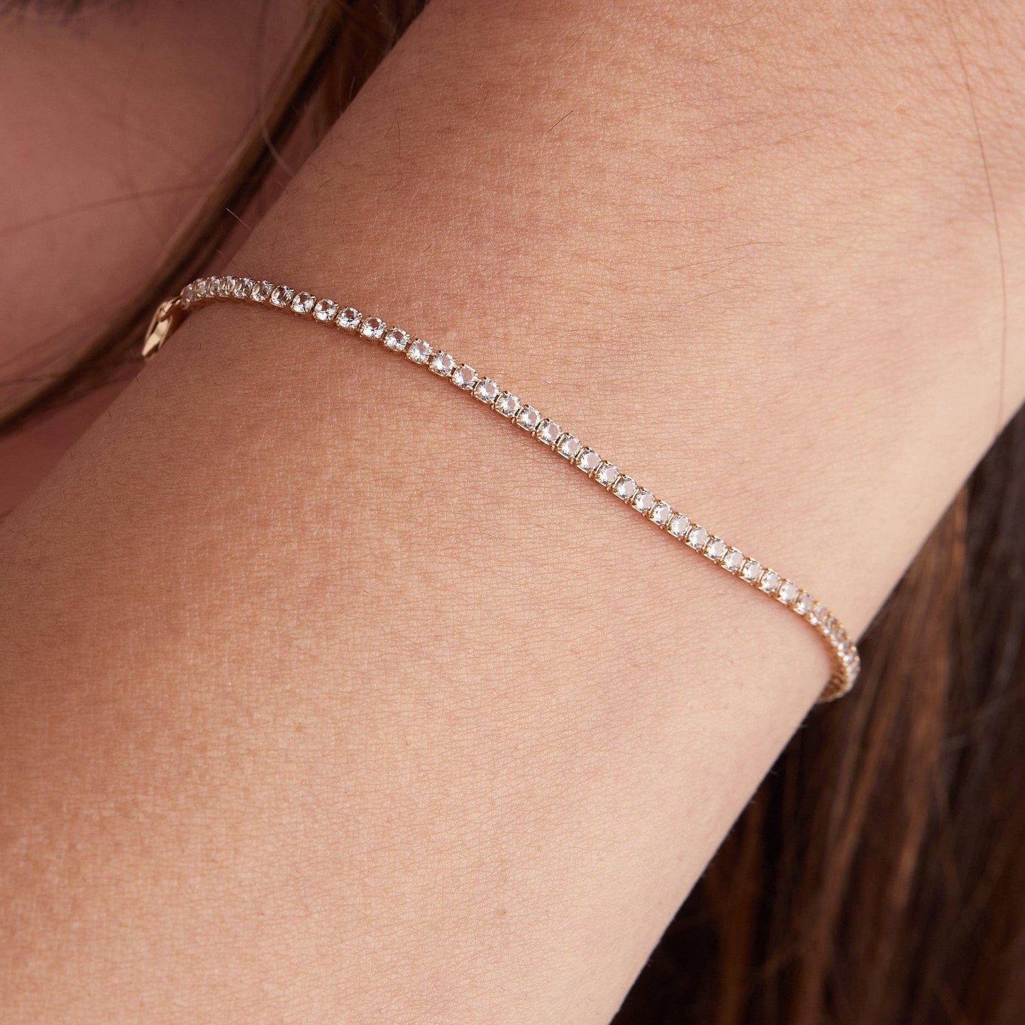 Rose gold bracelet on a person's wrist with a blurred background