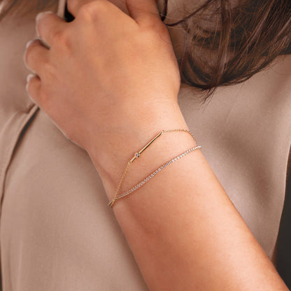 Close-up of a person's wrist wearing multiple gold bracelets on a neutral background