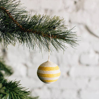 Decorative striped ornament hanging on a Christmas tree branch with a blurred snowy background