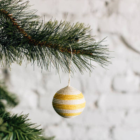 Decorative striped ornament hanging on a Christmas tree branch with a blurred snowy background
