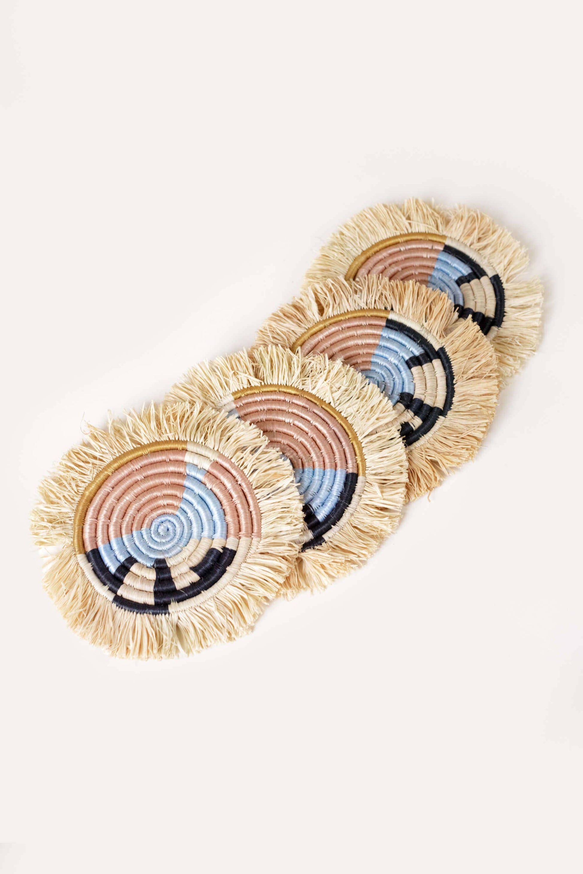 Set of four woven coasters with colorful patterns on a light background