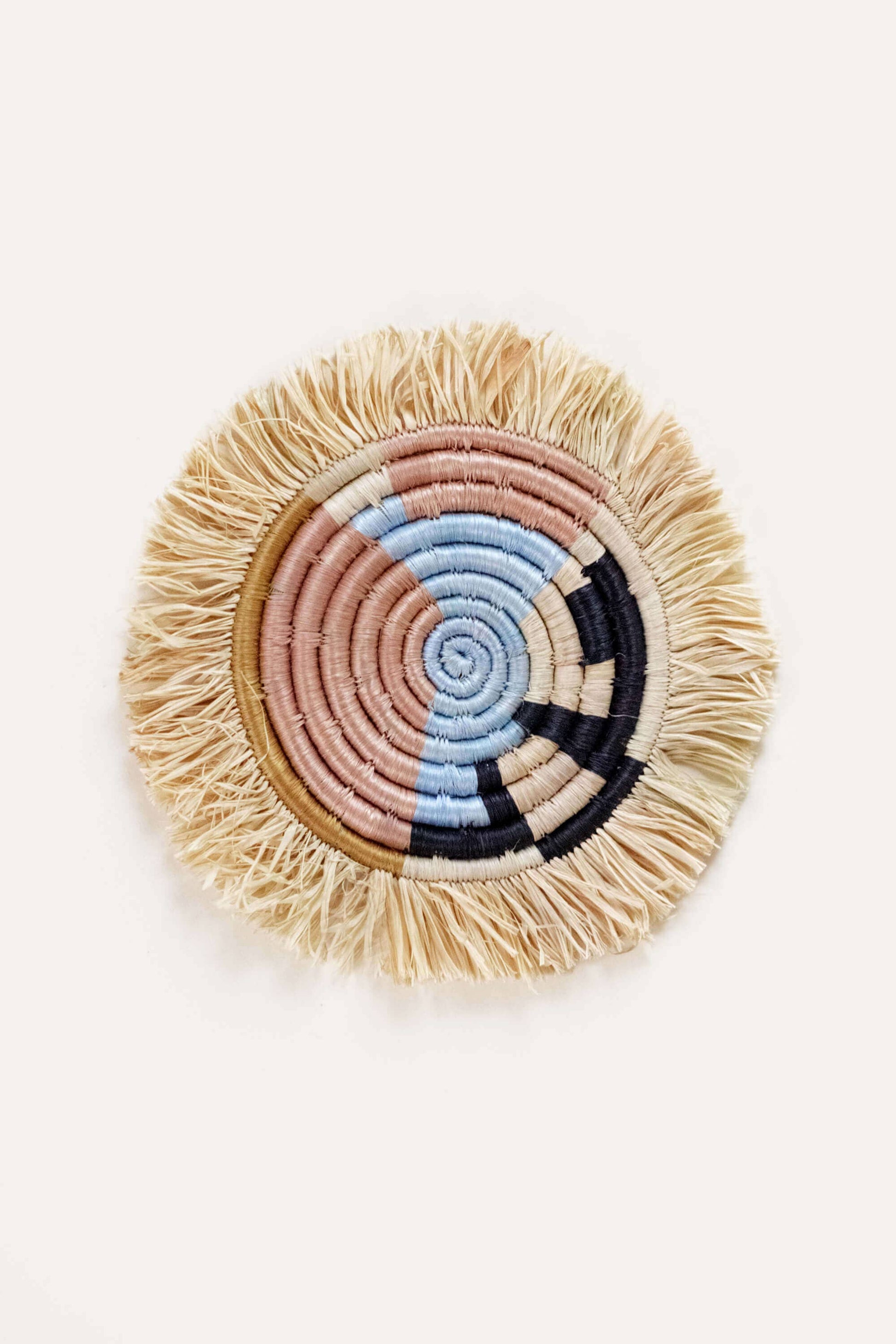 Round woven coaster with colorful spiral design on a white background