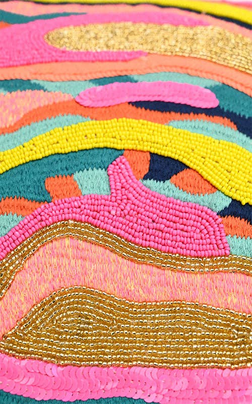 Close-up of a colorful beaded fabric with pink, yellow, and gold patterns.