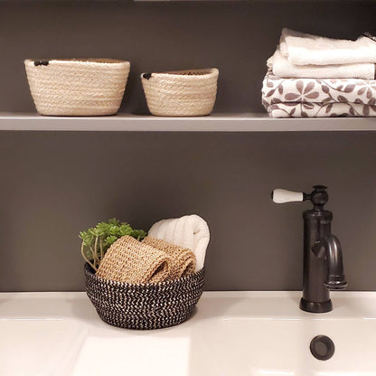 Baskets with towels and a plant on a sink counter next to a faucet.