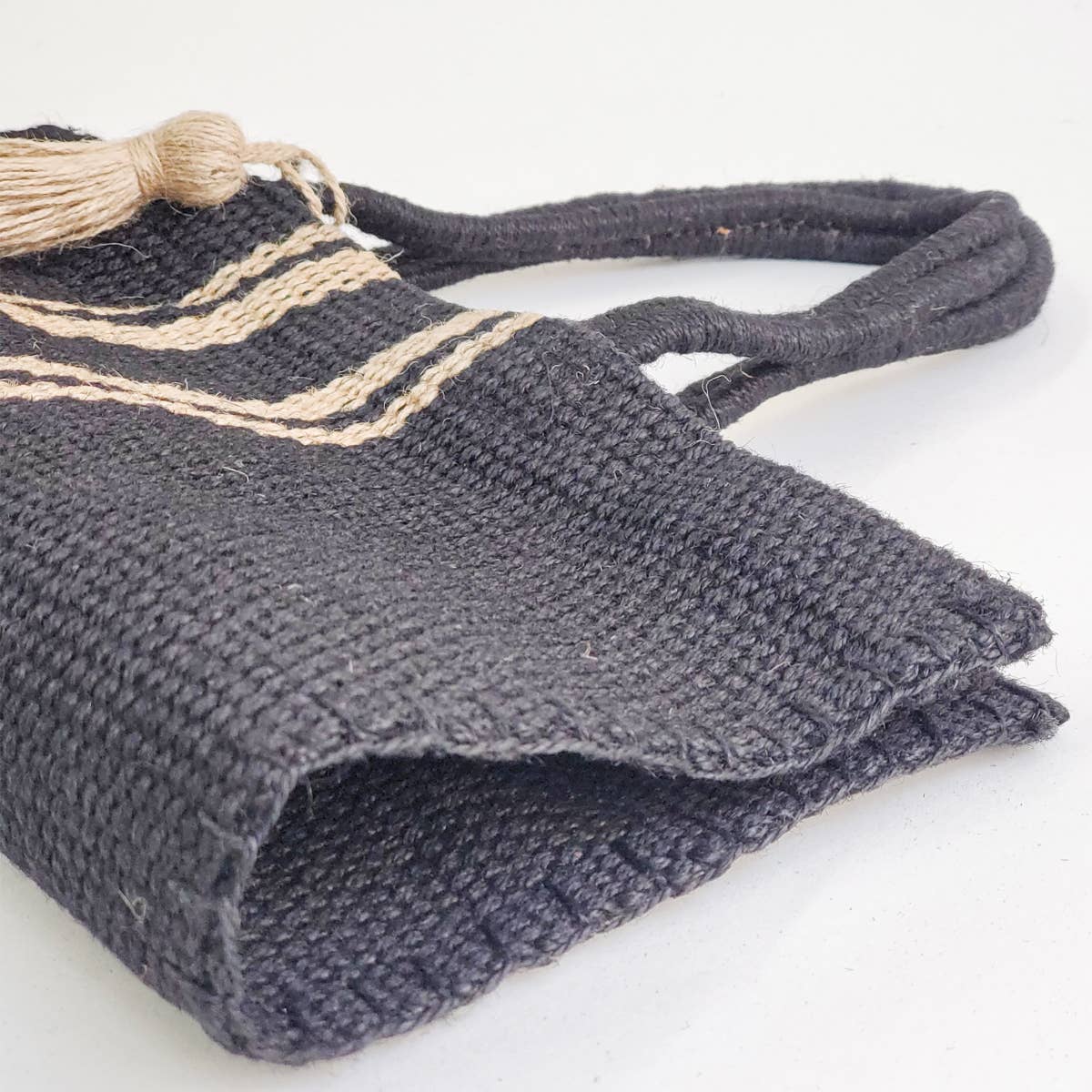 Black woven bag with beige accents on a white background