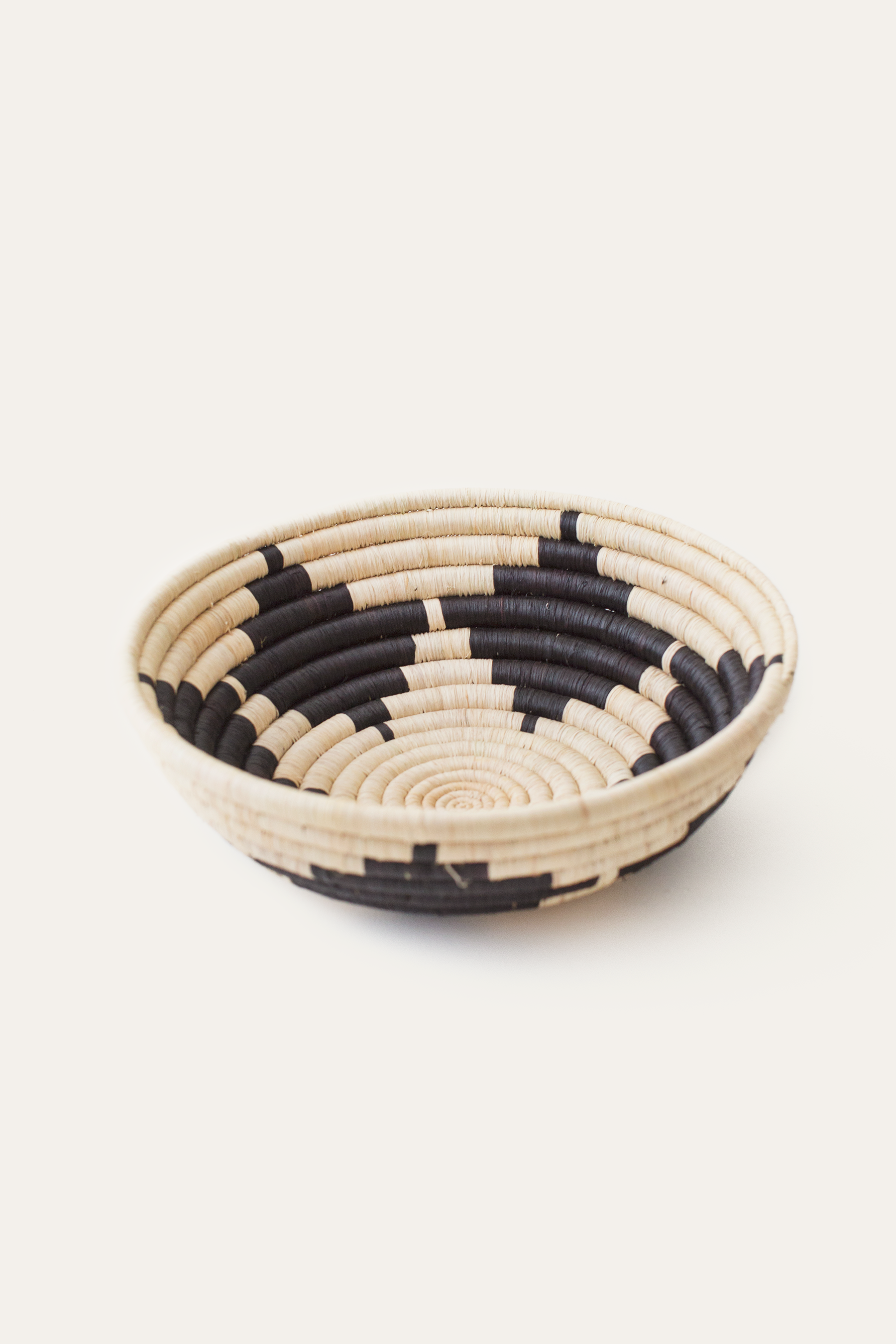 Woven basket with black and beige pattern on a white background