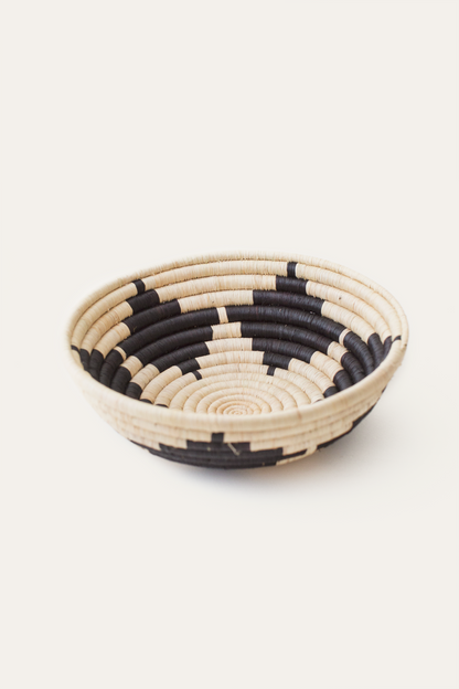 Woven basket with black and beige pattern on a white background