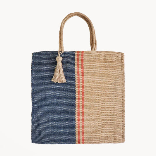 Woven tote bag with blue and beige sections and a tassel on a white background
