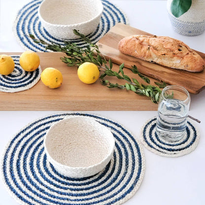 Table setting with blue and white woven coasters, lemons, bread, and a glass of water.
