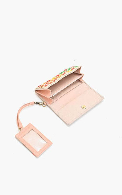 Pink wallet with floral design on the flap and matching luggage tag on a white background