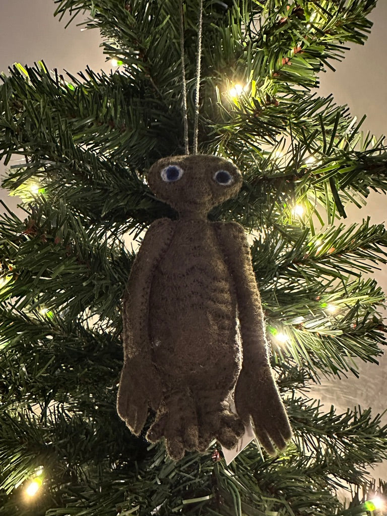 Felted brown creature ornament hanging on a lit Christmas tree.