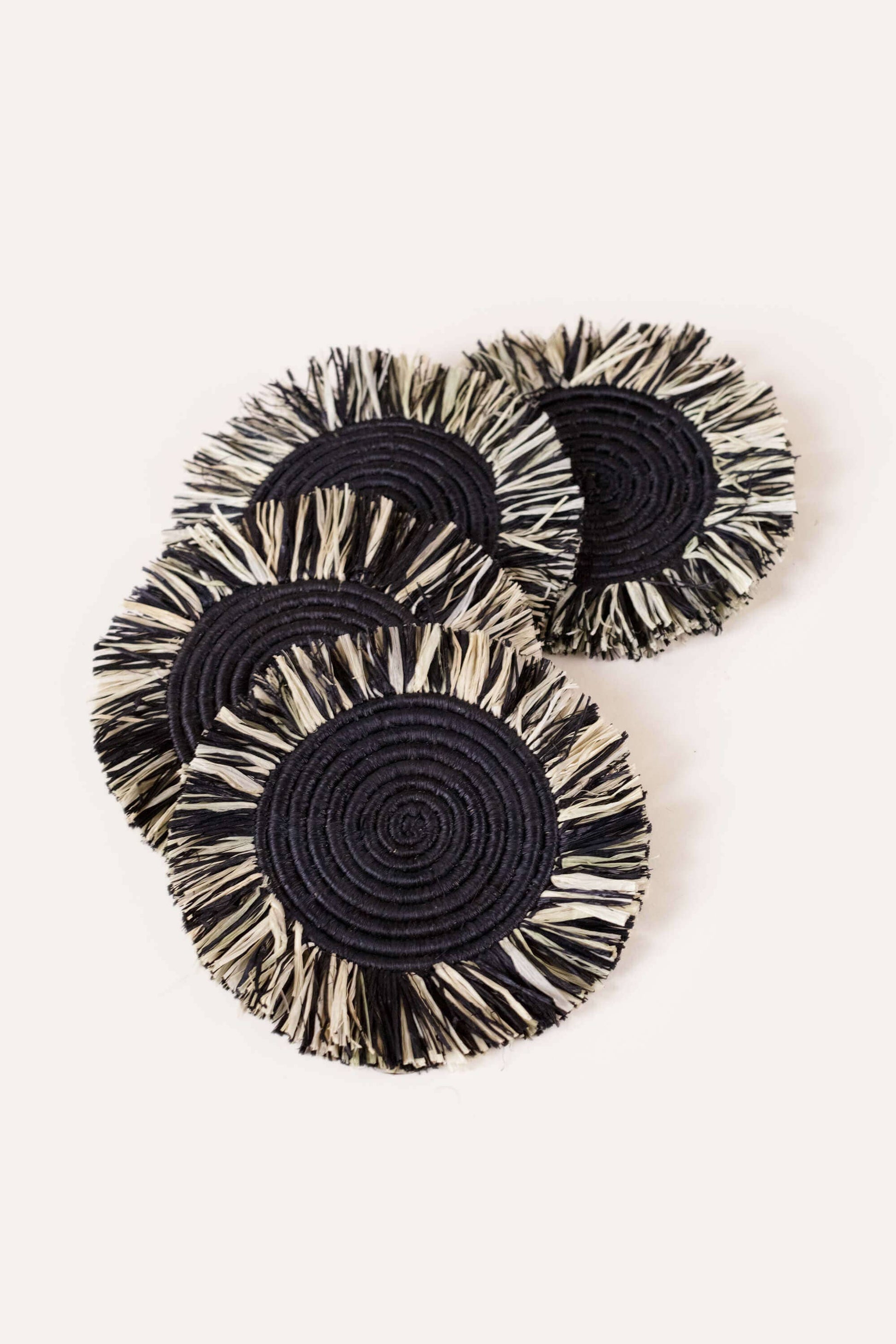 Set of four black and white circular coasters on a white background
