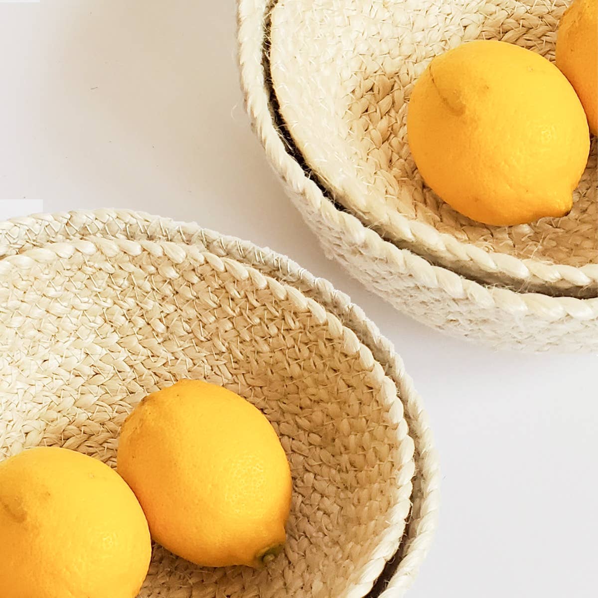 Four woven baskets with lemons on a light background