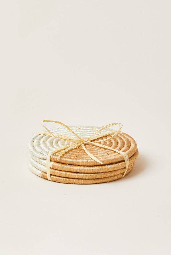 Set of round woven coasters in natural and white on a light beige background
