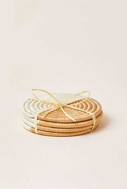 Set of round woven coasters in natural and white on a light beige background