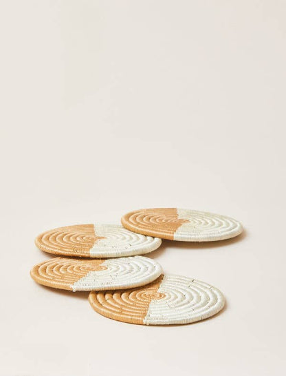Set of four round woven coasters with half beige and half white design on a light beige background