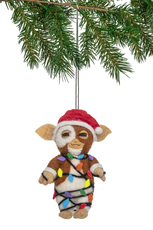 Felt ornament of a character wrapped in Christmas lights hanging from a tree branch.