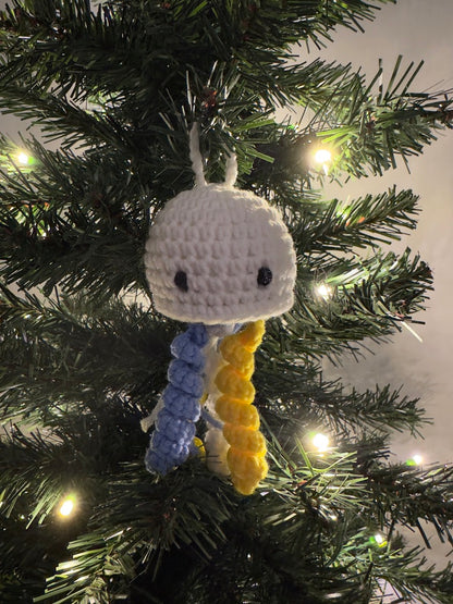 Crocheted jellyfish ornament hanging on a Christmas tree with lights.