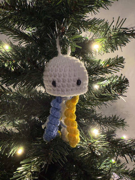 Crocheted jellyfish ornament hanging on a Christmas tree with lights.