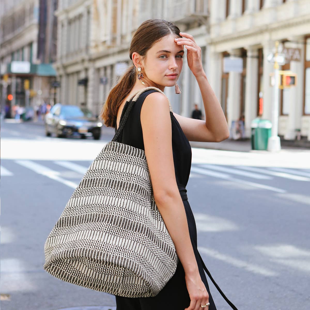 Woman carrying a large woven bag on a city street
