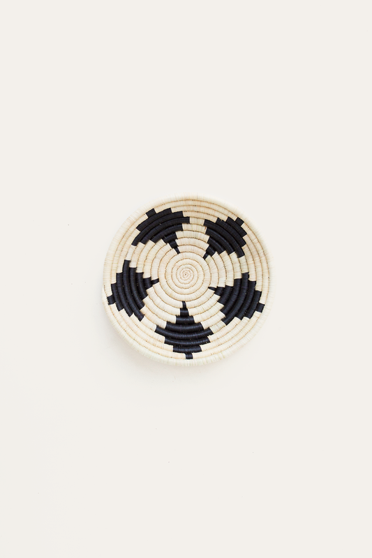 Round woven coaster with black and white pattern on a beige background