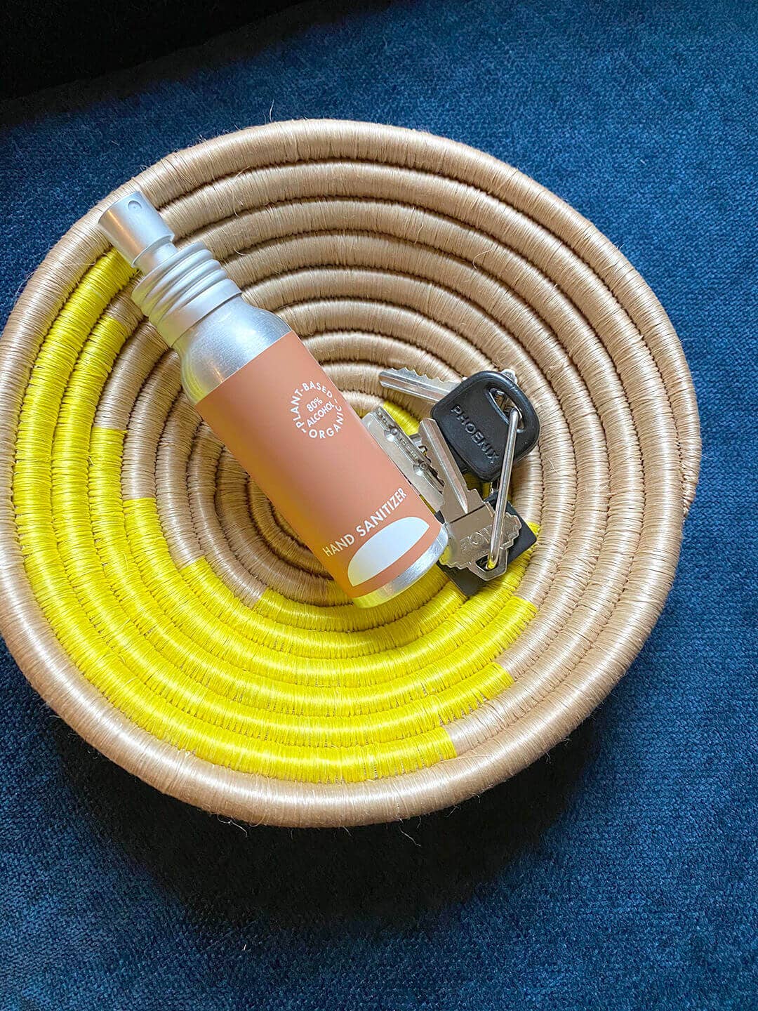 Coiled basket with a bottle and keys on a blue background