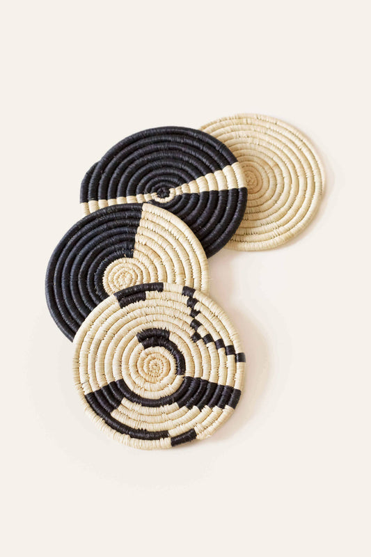 Set of black and beige woven coasters on a light background