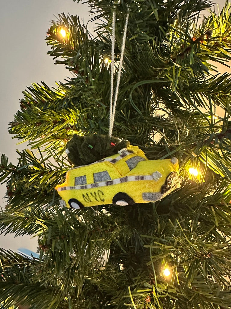 Yellow taxi cab ornament on a decorated Christmas tree with lights.