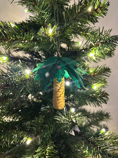 Decorative palm tree ornament on a Christmas tree with lights.