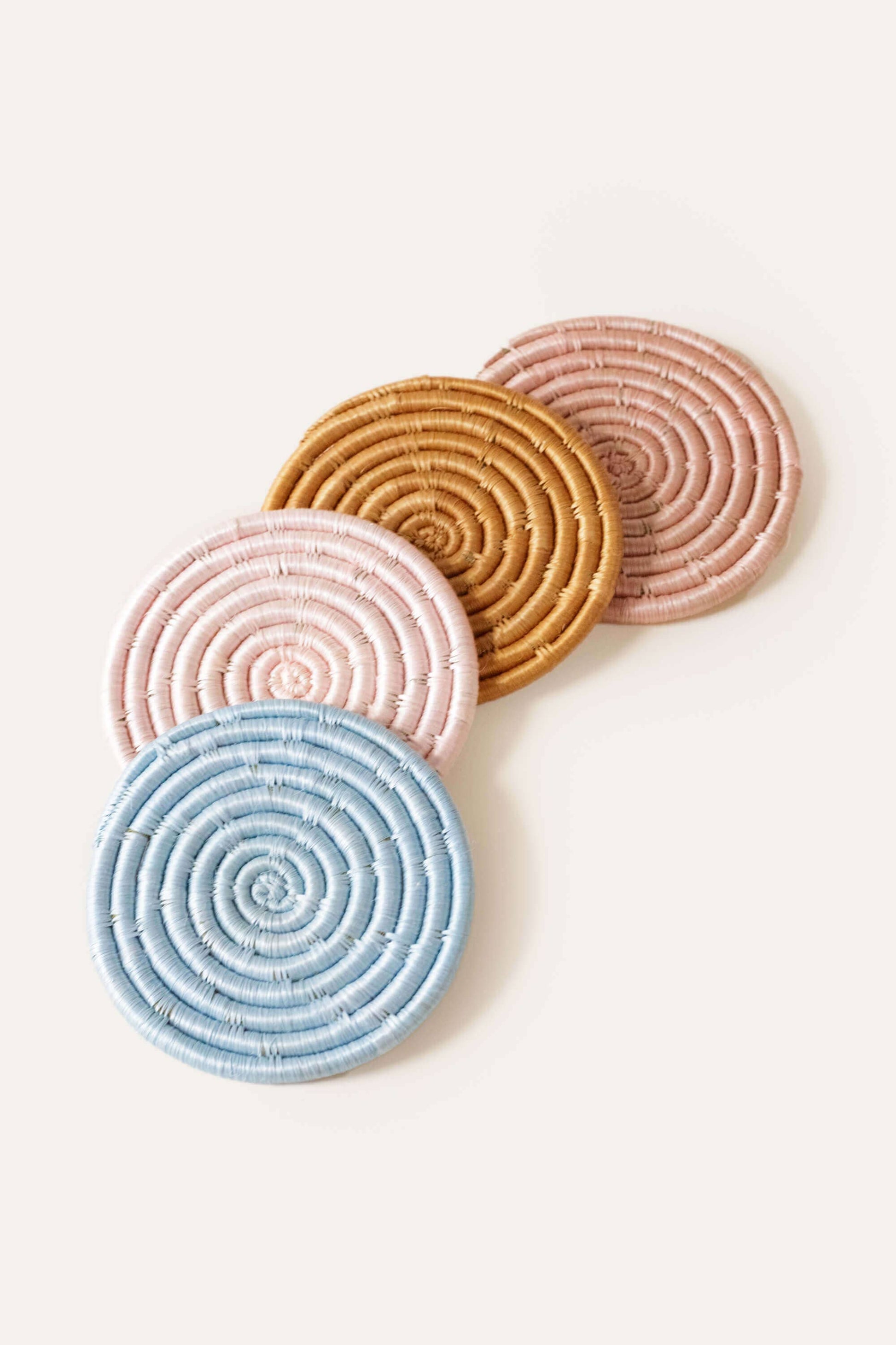 Four circular coasters in pink, blue, and brown on a light background