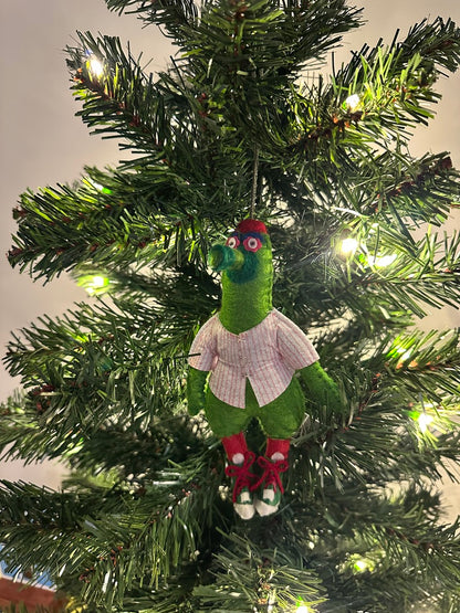 Green creature ornament in a jersey hanging on a decorated Christmas tree.