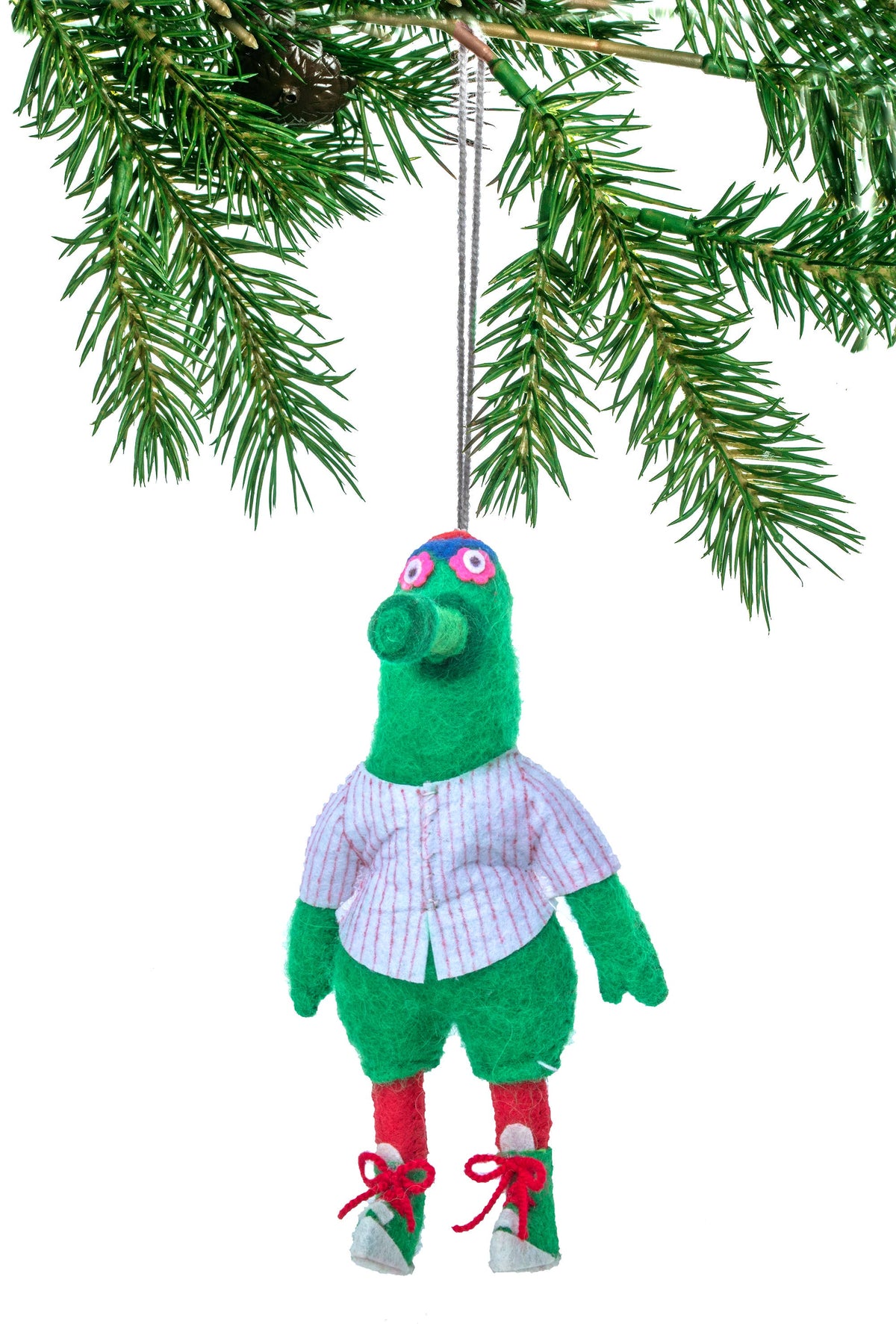 Green plush toy with a white shirt hanging from a Christmas tree branch.