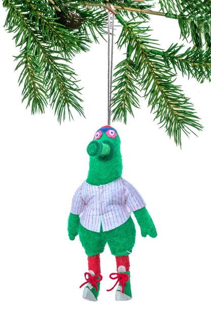 Green plush toy with a white shirt hanging from a Christmas tree branch.