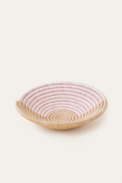 Round woven basket with pink top and natural base on a white background