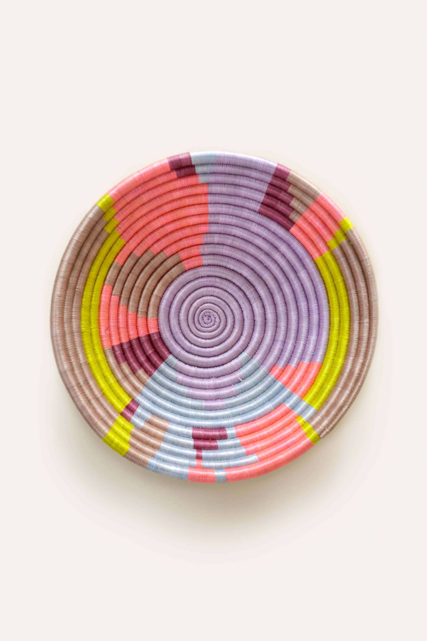 Colorful woven basket with concentric circle pattern on a white background
