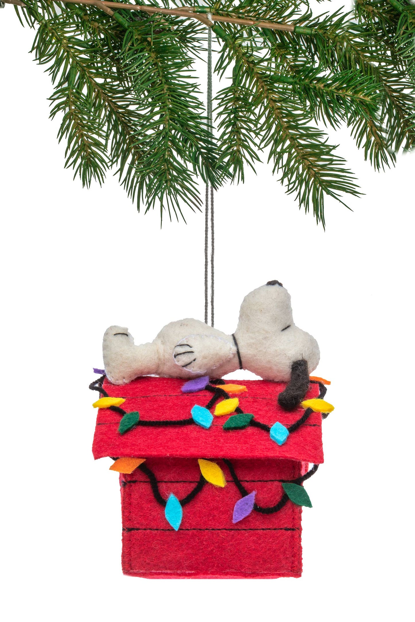 Christmas ornament with Snoopy and Woodstock on a red doghouse with lights, hanging from a tree branch.