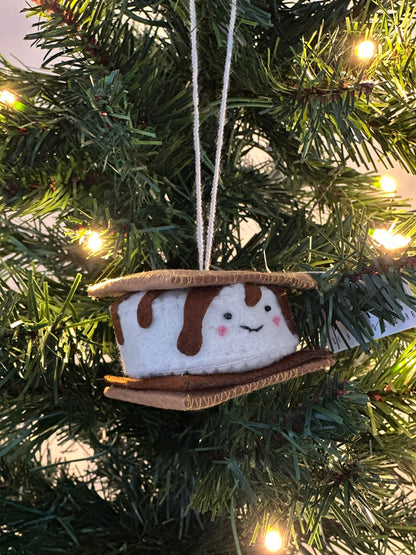 S'mores ornament hanging on a Christmas tree with lights.
