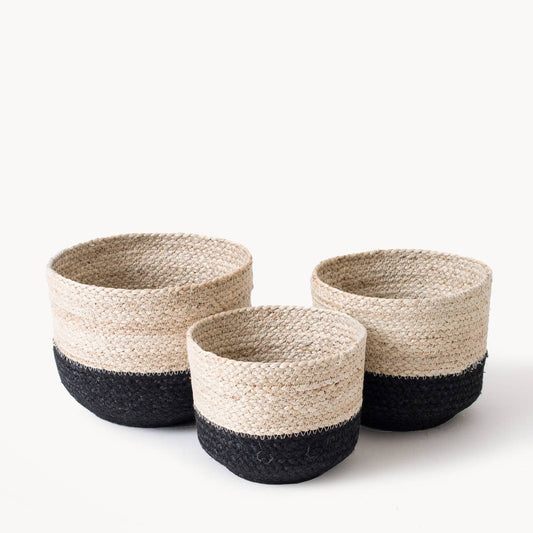 Three woven baskets with black and natural color scheme on a white background