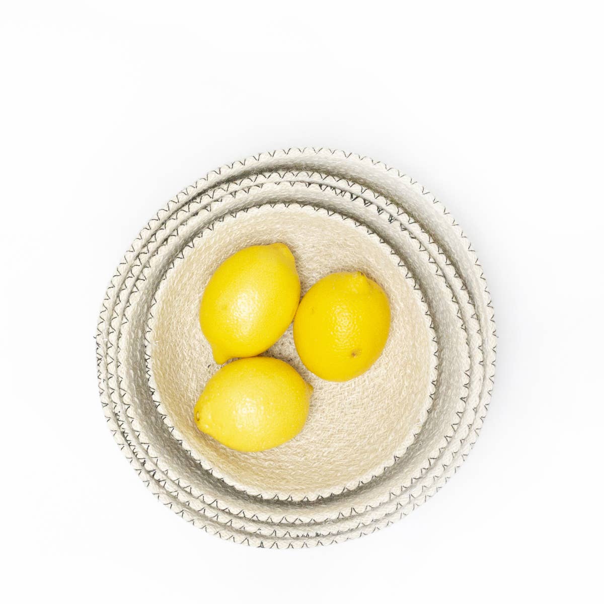 Three lemons in a woven basket on a white background